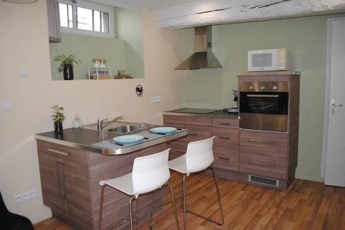 a kitchen with a sink and two white chairs at Appartement dans bâtiment du 18ème siècle in Argentan