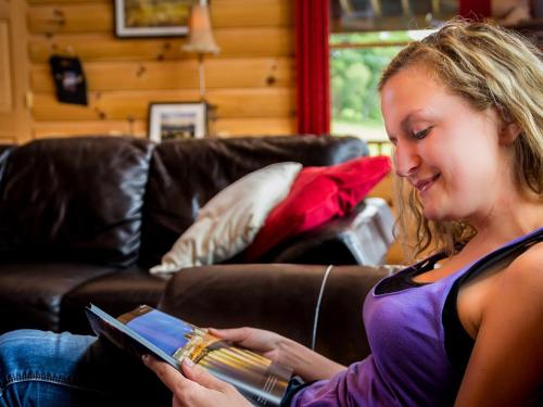 a young woman sitting on a couch reading a book at Eaglewood Lodge Connemara and Mayo in Carrowkennedy