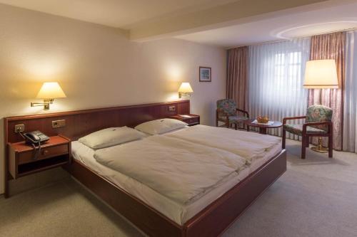 a hotel room with a large bed and two chairs at Hotel Altdeutsche Weinstuben in Freyburg