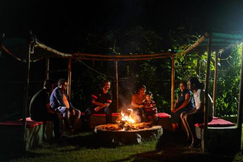 a group of people sitting around a fire at night at Cottages @ Village in Nainital