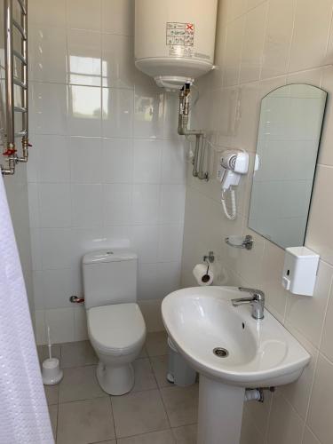 a white bathroom with a toilet and a sink at ZIG ZAG in Kamianets-Podilskyi