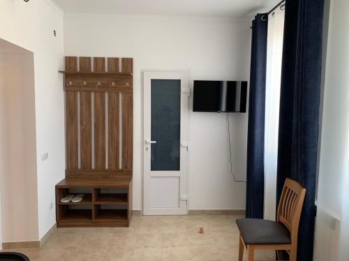 Zimmer mit einer Tür, einem Stuhl und einem TV in der Unterkunft ZIG ZAG in Kamjanez-Podilskyj