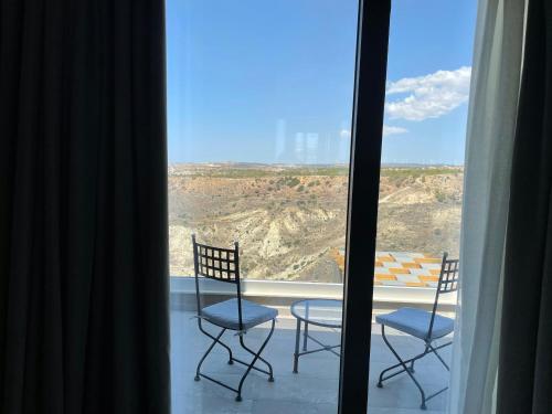 a balcony with two chairs and a view of the desert at Windhill Edge Villa in Pissouri
