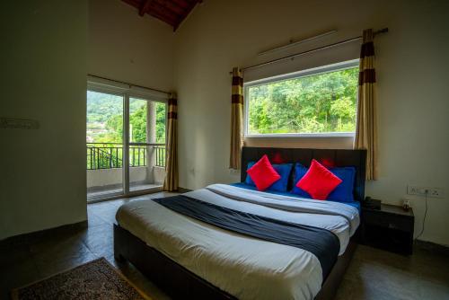 a bedroom with a bed with red and blue pillows at Cottages At Village Bhimtal-Naukuchiatal in Bhīm Tāl