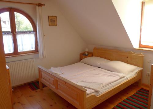1 dormitorio con cama de madera en el ático en Aranyház Apartmanszállás, en Tihany