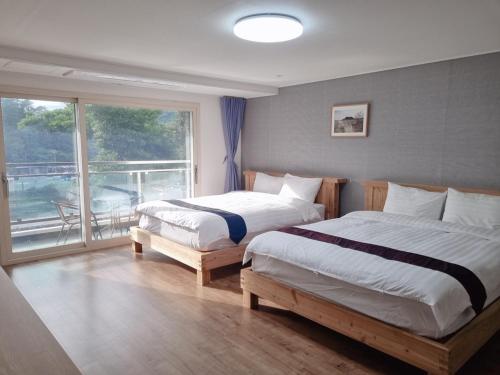 a bedroom with two beds and a large window at Cheonjiyeon Crystal Hotel in Seogwipo