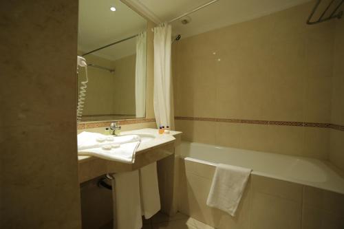 a bathroom with a sink and a bath tub at Hotel Suisse in Casablanca