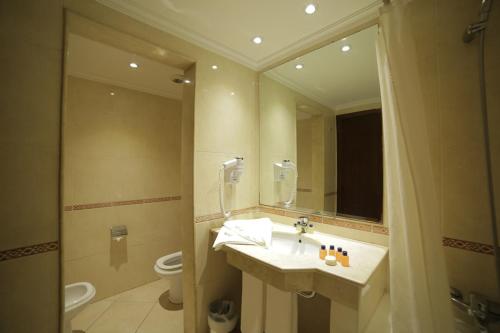 a bathroom with a sink and a toilet and a mirror at Hotel Suisse in Casablanca