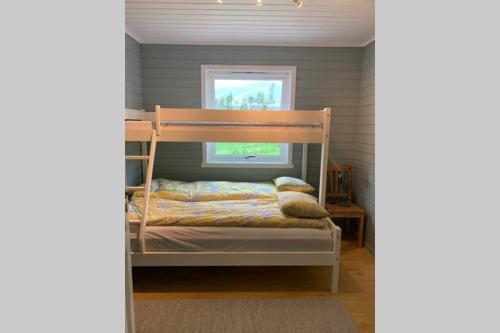 a bedroom with a bunk bed and a window at Efjord and Stetind Resort - Cabin Kobbernestinden in Ballangen