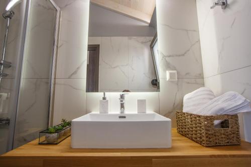 La salle de bains est pourvue d'un lavabo blanc et d'un miroir. dans l'établissement Théa boutique villas sivota II, à Sivota