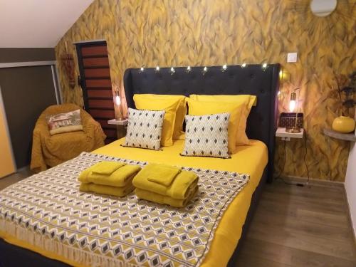 1 dormitorio con 1 cama con sábanas y almohadas amarillas en CHAMBRE CHEZ L HABITANT PISCINE VUE MER SDB et TERRASSE PRIVEE, en Saint-Pierre