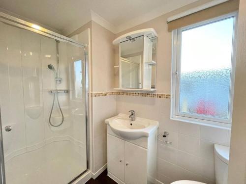 uma casa de banho branca com um chuveiro e um lavatório. em Modern House in Carlisle close to Lake District em Carlisle