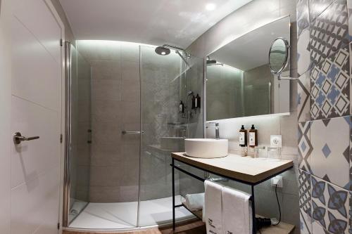 a bathroom with a glass shower and a sink at Petit Palace Ruzafa in Valencia