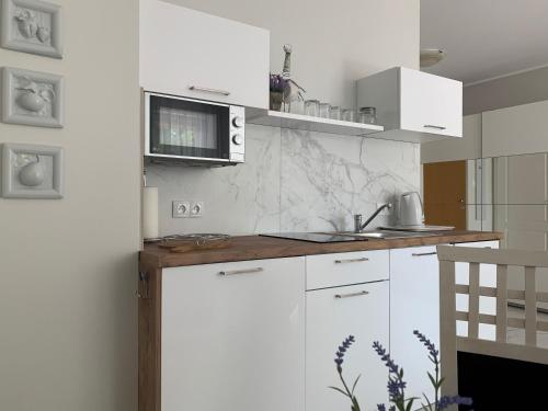 a kitchen with white cabinets and a microwave at Apartament Sloneczny in Kołobrzeg