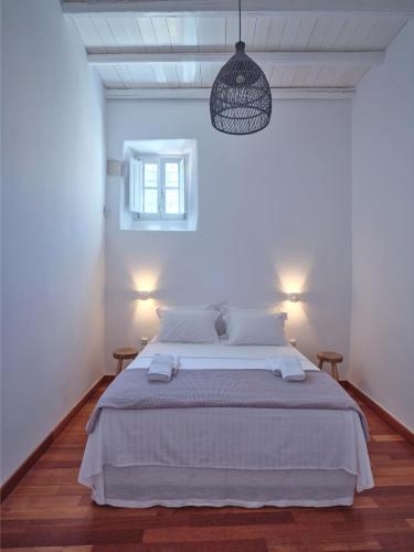 a white bedroom with a bed and a pendant light at Retreat Paros - The Door Apartment in Parikia