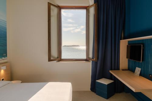 a bedroom with a window with a view of the ocean at Isola di San Servolo - Centro Soggiorno in Venice