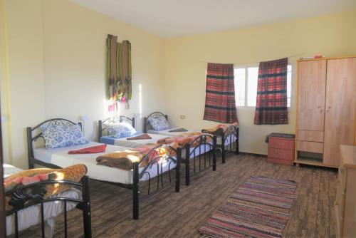 a room with four beds and a couch and windows at Happy Bedouin House Petra in Al Ḩayy