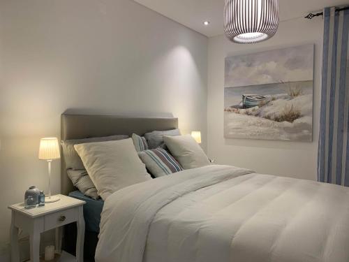 een slaapkamer met een bed en een schilderij aan de muur bij CasaBlanca - Haus am Meer in Fuzeta