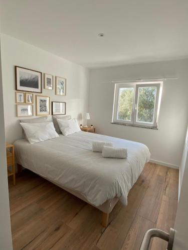 a white bedroom with a large bed with a window at Your Home @ Benagil in Lagoa