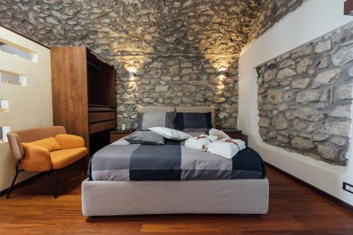 a bedroom with a stone wall with a bed and a chair at Vicolo72 in Calitri