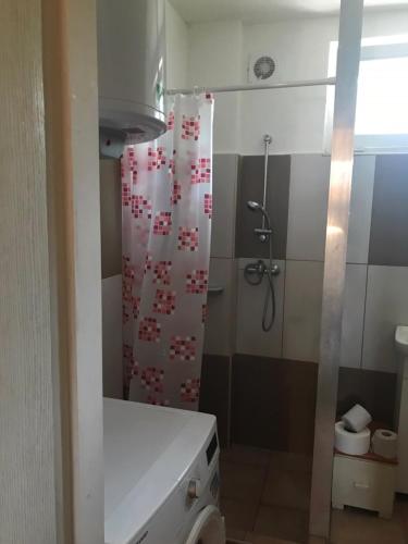 a bathroom with a shower with a red and white curtain at Balogh vendégház II in Szeged