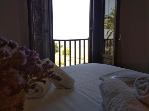 a bedroom with a bed with a view of a balcony at TERRA LEMNIA in Moudhros