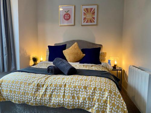 a bed with blue and gold pillows on it at Funky Stylish Apartment! - 5 Minute Walk to the Best Beach! - Great Location - Parking - Fast WiFi - Smart TV - Newly decorated - sleeps up to 4! Close to Bournemouth & Poole Town Centre & Sandbanks in Bournemouth