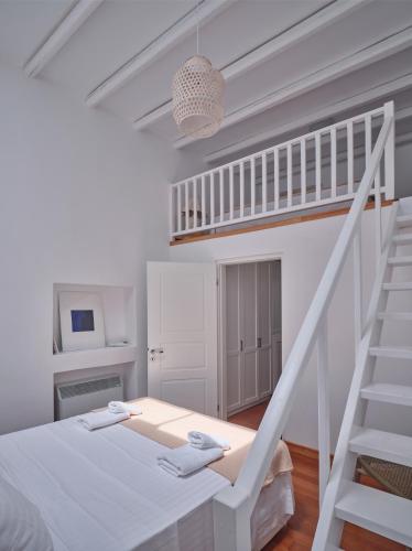 a white room with a bed and a staircase at Retreat Paros - The Loft Apartment in Parikia