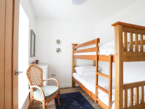 a room with a bunk bed and a chair at Bryn Afon Farm in Caernarfon