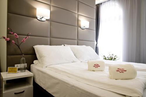 a bedroom with a large white bed with two pillows at Plovdiv City Center Hotel in Plovdiv