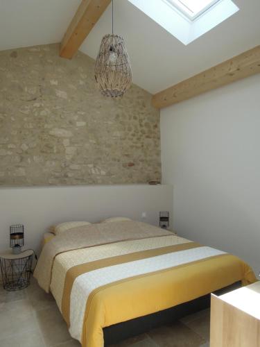 ein Schlafzimmer mit einem Bett und einer Steinmauer in der Unterkunft La Bourgade in Céreste