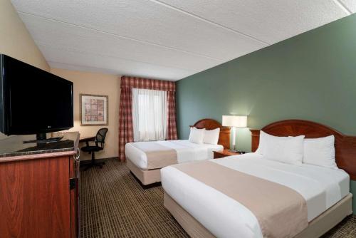 a hotel room with two beds and a flat screen tv at Baymont by Wyndham Knoxville/Cedar Bluff in Knoxville