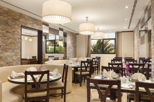 a dining room with tables and chairs and windows at Ramada Hotel & Suites by Wyndham Ajman in Ajman 