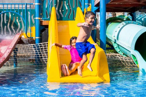 two children playing on a slide at a water park at The Art Hotel & Resort in Manama