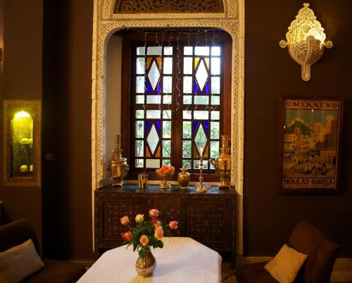 a room with a table and a window with a vase of flowers at Riad El Arsat & Spa in Marrakech