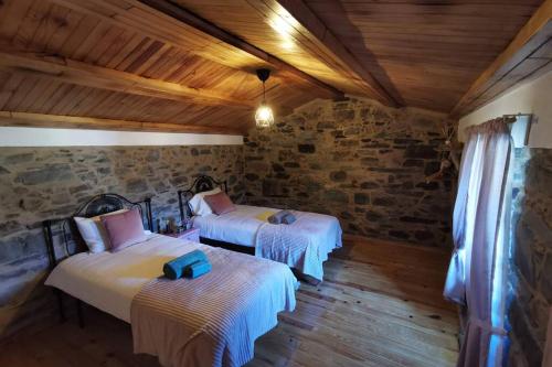 2 letti in una camera con parete in pietra di Casa do Linho 400 year old country cottage a Oleiros