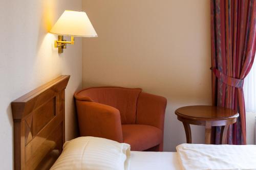 a room with a chair and a table and a lamp at Hotel Garni Schlossgarten in Neustrelitz