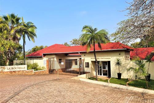 una casa con techo rojo y palmeras en First Group La Rochelle, en St Lucia