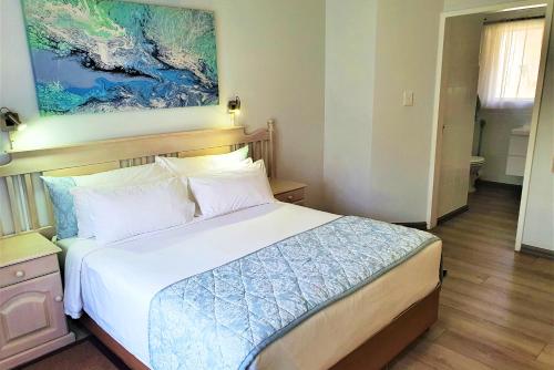 1 dormitorio con 1 cama y una pintura en la pared en First Group La Rochelle, en St Lucia