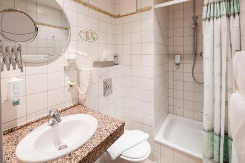 a bathroom with a sink and a toilet and a tub at Hotel Garni Schlossgarten in Neustrelitz