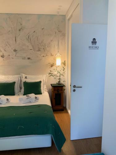 a bedroom with a green and white bed and a door at Casa da Zéfinha, em Cinfães, no Douro in Cinfães
