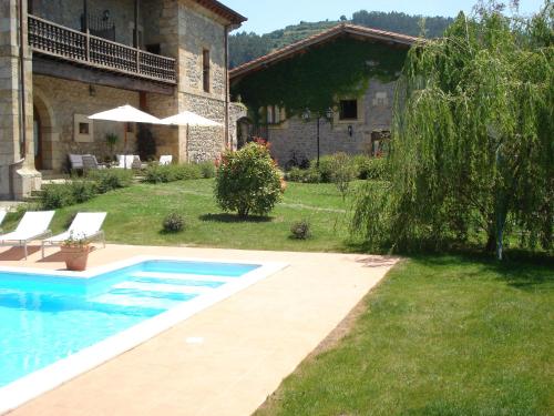 a swimming pool in the yard of a house at Hotel Palacio Garcia Quijano in Los Corrales de Buelna
