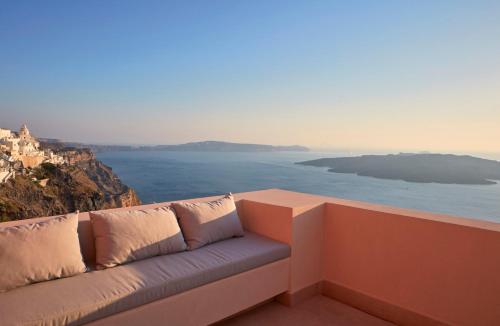 a couch sitting on a balcony overlooking the ocean at Villa Bordeaux in Fira