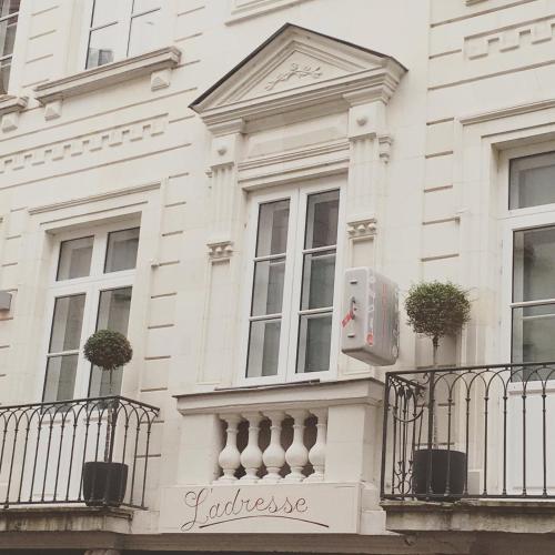 a white building with a balcony and a box on it at Hôtel L'Adresse in Tours