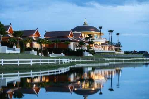 a house with a reflection in the water at Thantara Resort Chiang Mai in Chiang Mai