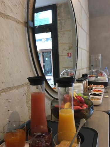 a counter with two bottles of juice and a mirror at Hôtel L'Adresse in Tours