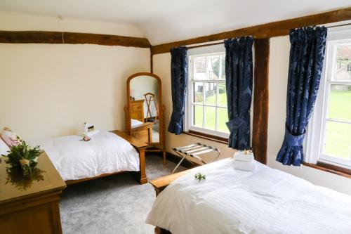 a bedroom with two beds and two windows at Little Easton Manor in Great Easton