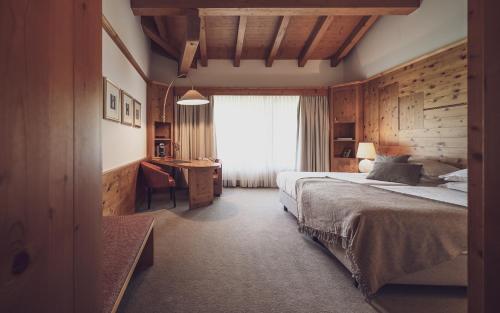 Schlafzimmer mit einem Bett, einem Schreibtisch und einem Fenster in der Unterkunft Hotel Waldhuus in Davos