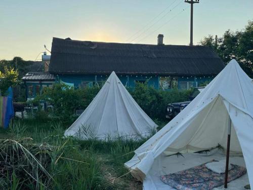 two white tents in the grass in front of a building at Danube Delta Hostel Homestay & Camping in Sulina