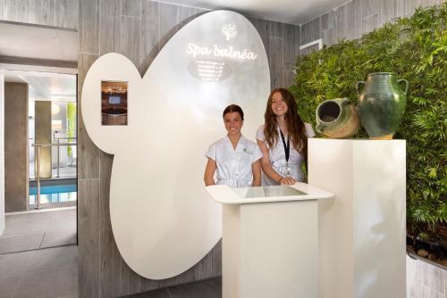 a man and a woman standing at a counter in a room at Terre de Provence Hôtel & Spa in Le Pontet
